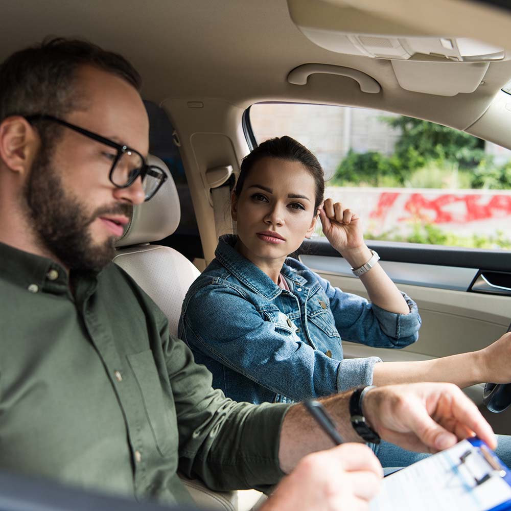 Nervous female student and male teacher in car driving